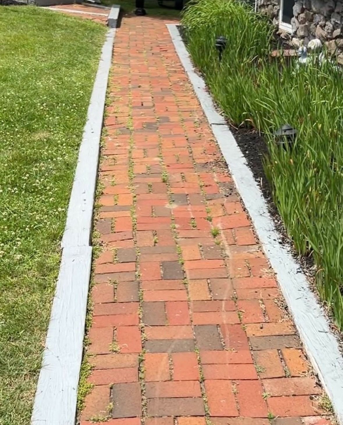 Worn brick paver walkway with wood edging prior to renovation